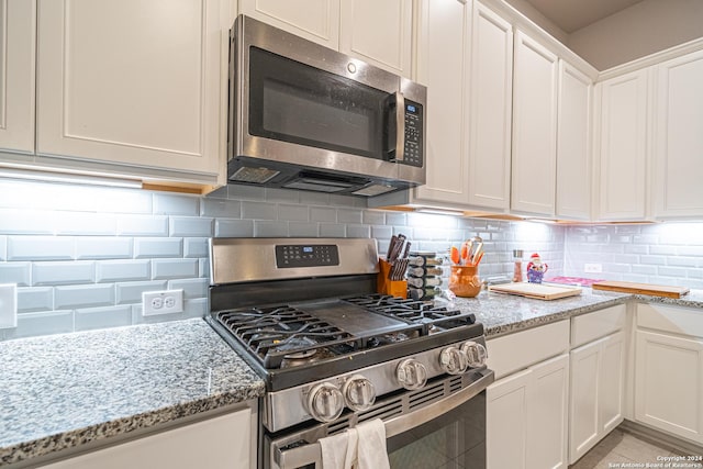 kitchen featuring light stone counters, white cabinetry, and stainless steel appliances