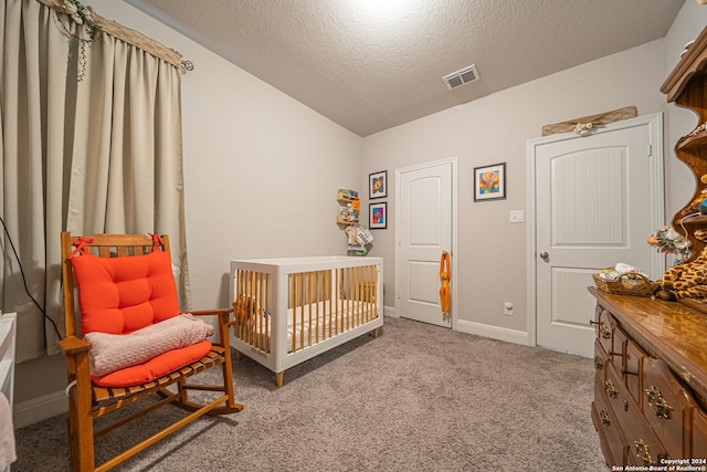 bedroom with a textured ceiling, light carpet, vaulted ceiling, and a crib