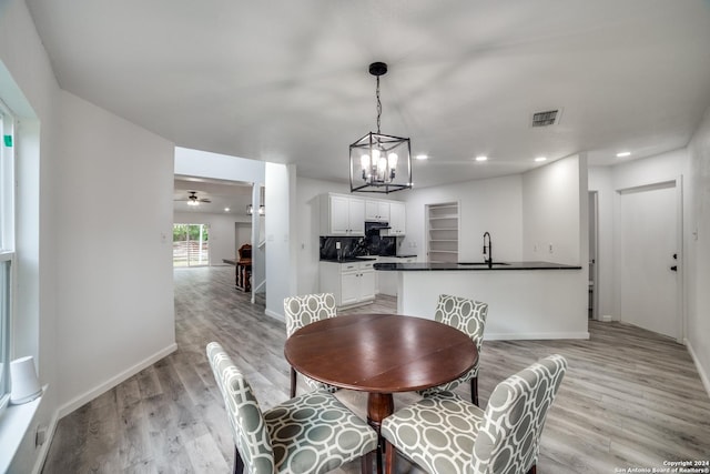 dining space featuring ceiling fan with notable chandelier, sink, and light hardwood / wood-style flooring