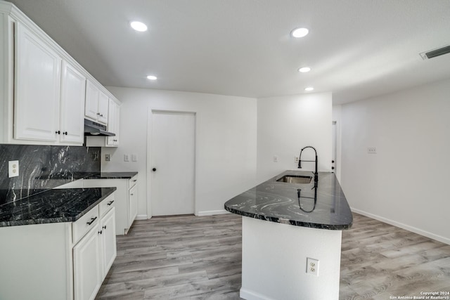 kitchen with tasteful backsplash, sink, white cabinets, and light hardwood / wood-style flooring