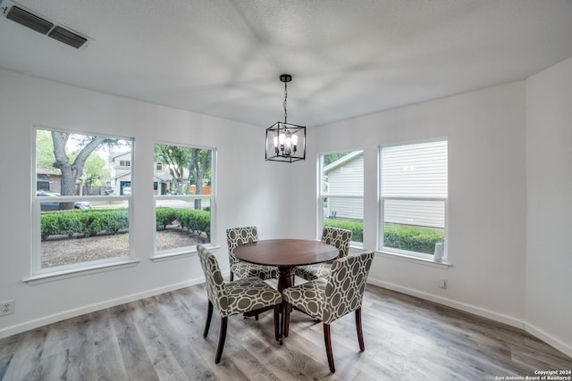 dining area with hardwood / wood-style flooring, a textured ceiling, and a chandelier