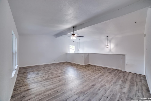 spare room with ceiling fan, lofted ceiling with beams, a textured ceiling, and light hardwood / wood-style flooring