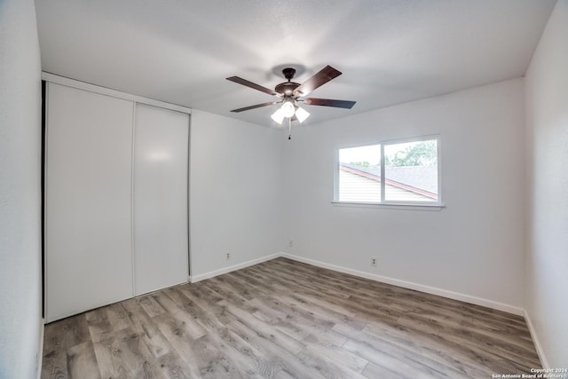 unfurnished bedroom with a closet, light hardwood / wood-style flooring, and ceiling fan