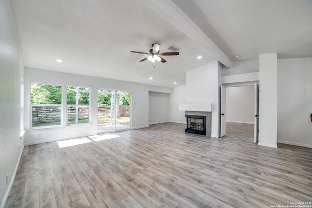 unfurnished living room with a tiled fireplace, ceiling fan, and light hardwood / wood-style flooring