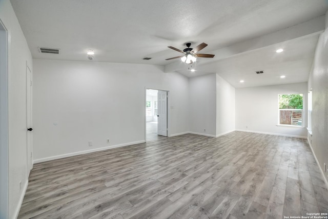 empty room featuring a textured ceiling, light wood-type flooring, ceiling fan, and lofted ceiling