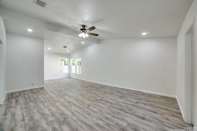 spare room featuring a textured ceiling, ceiling fan, vaulted ceiling, and light wood-type flooring