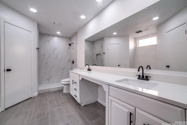 bathroom with toilet, vanity, and tiled shower