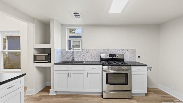 kitchen with gas stove, white cabinetry, and plenty of natural light