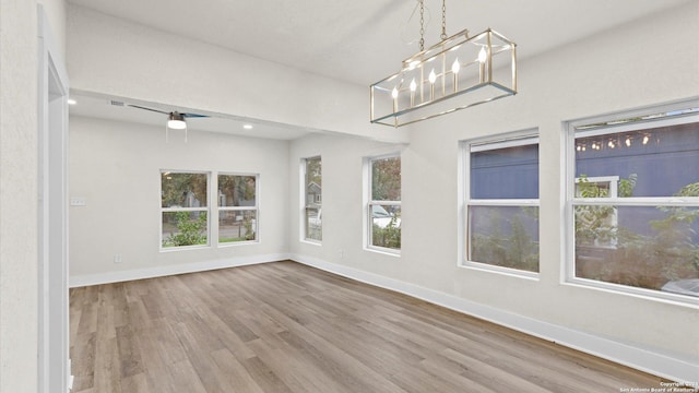 interior space featuring hardwood / wood-style floors, ceiling fan with notable chandelier, and a wealth of natural light