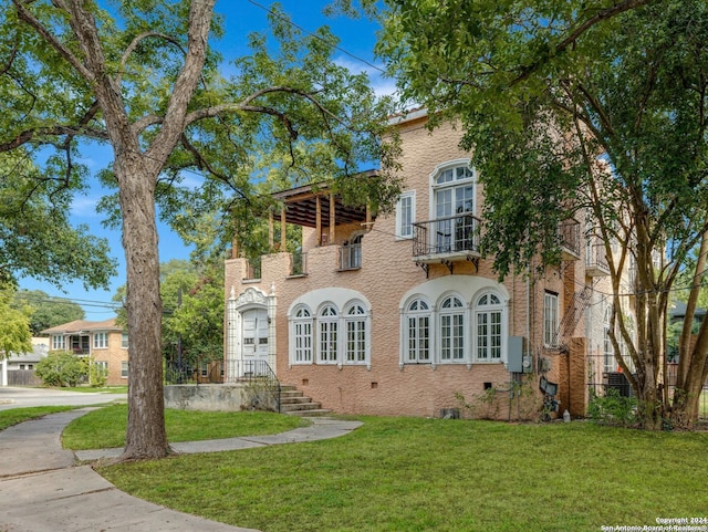 view of front of property featuring a balcony and a front yard