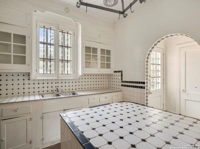 kitchen featuring tasteful backsplash, white cabinetry, a healthy amount of sunlight, and sink