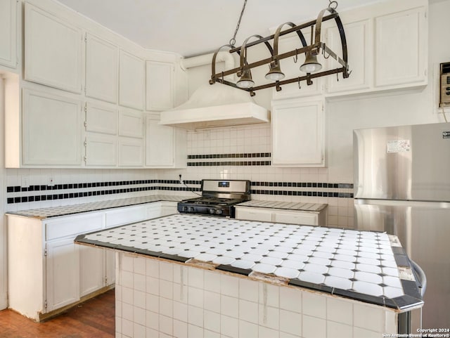 kitchen featuring appliances with stainless steel finishes, dark hardwood / wood-style flooring, backsplash, white cabinets, and hanging light fixtures