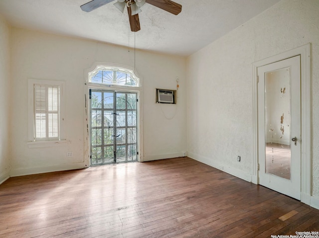 empty room with hardwood / wood-style flooring, ceiling fan, a healthy amount of sunlight, and a wall mounted AC