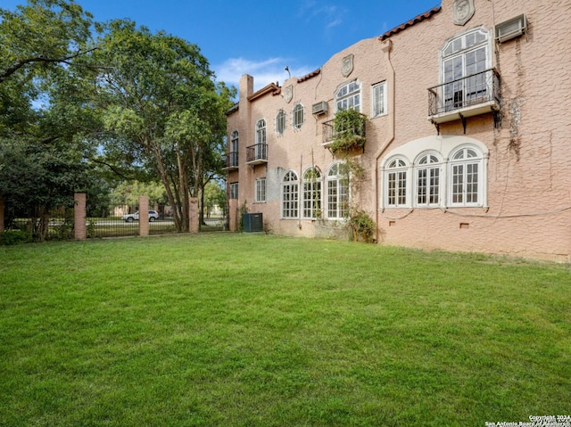 exterior space featuring a wall mounted air conditioner, central AC, and a lawn