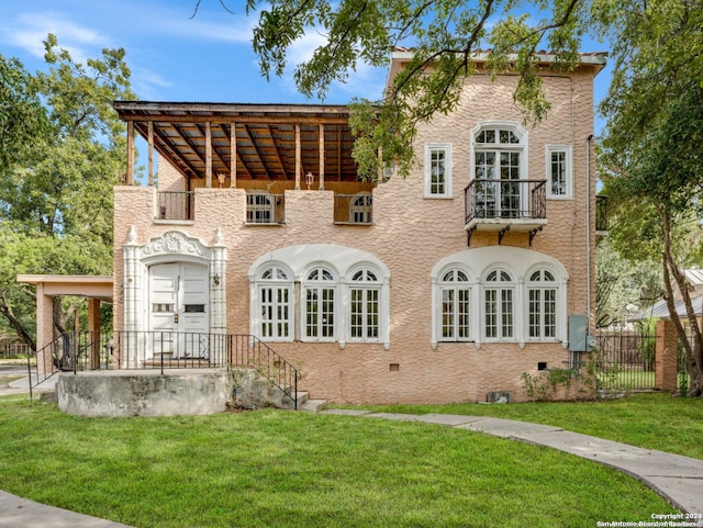 back of house featuring a balcony and a lawn