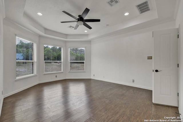 empty room featuring ornamental molding, dark hardwood / wood-style floors, ceiling fan, and a tray ceiling