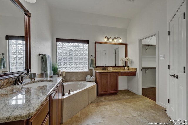 bathroom with vanity, lofted ceiling, and a bath