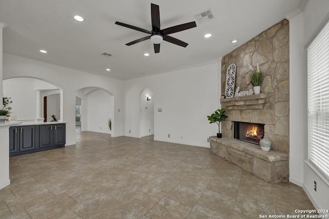 living room with ceiling fan, ornamental molding, and a fireplace