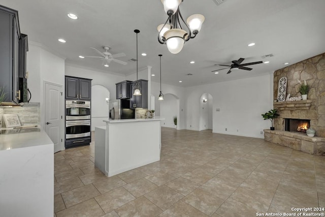 kitchen with ceiling fan, pendant lighting, a fireplace, a kitchen island, and appliances with stainless steel finishes