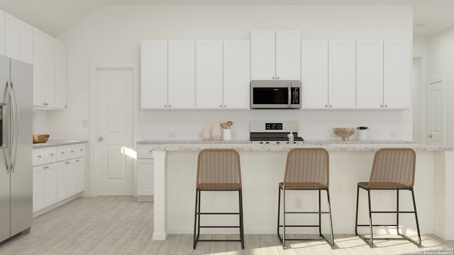 kitchen featuring white cabinets, a kitchen breakfast bar, stainless steel appliances, and an island with sink