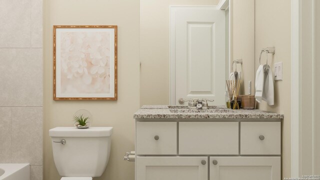 bathroom with vanity, toilet, and a tub to relax in