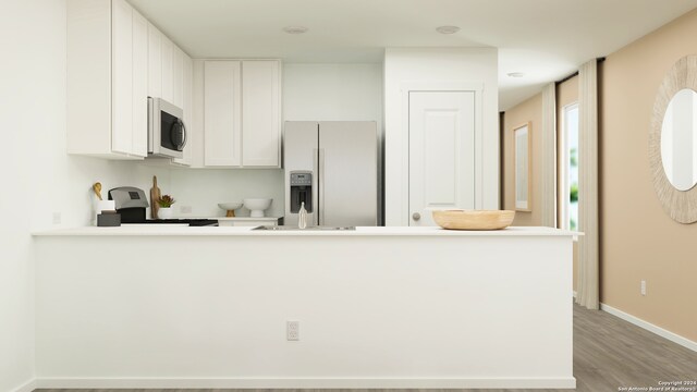 kitchen featuring white cabinetry, white refrigerator with ice dispenser, kitchen peninsula, light hardwood / wood-style floors, and range