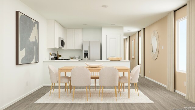 kitchen featuring kitchen peninsula, white fridge with ice dispenser, white cabinets, and light wood-type flooring