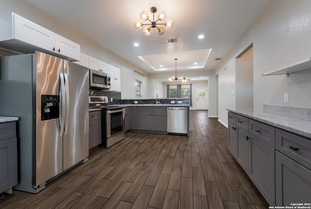 kitchen featuring kitchen peninsula, stainless steel appliances, dark wood-type flooring, an inviting chandelier, and hanging light fixtures