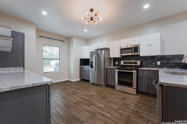 kitchen featuring dark hardwood / wood-style floors, light stone counters, white cabinetry, and appliances with stainless steel finishes