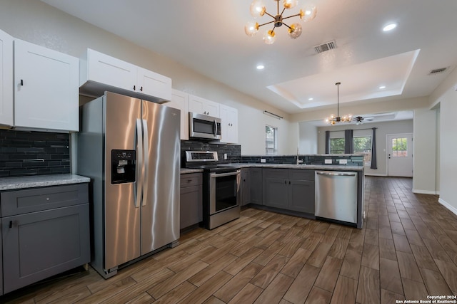 kitchen featuring gray cabinetry, ceiling fan with notable chandelier, hanging light fixtures, appliances with stainless steel finishes, and white cabinetry