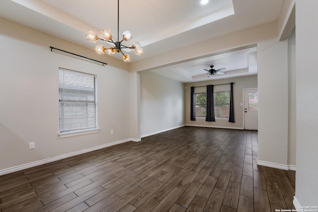 unfurnished room featuring ceiling fan with notable chandelier, dark hardwood / wood-style flooring, and a tray ceiling