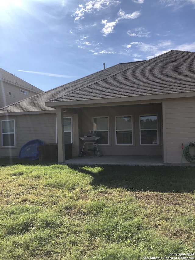 back of house featuring a lawn and a patio