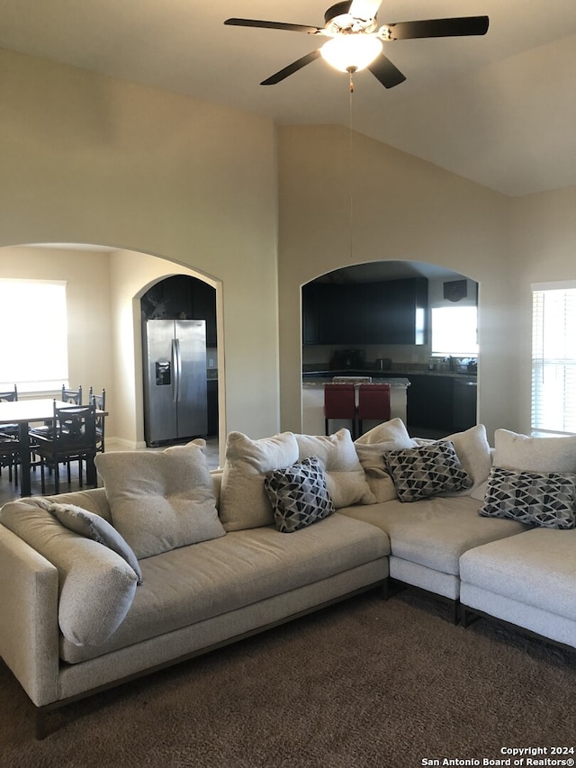 carpeted living room with ceiling fan and vaulted ceiling