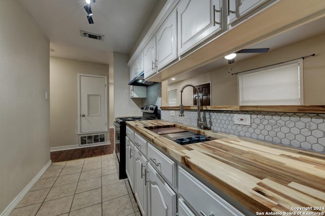 kitchen featuring tasteful backsplash, sink, light tile patterned floors, white cabinetry, and range with electric stovetop