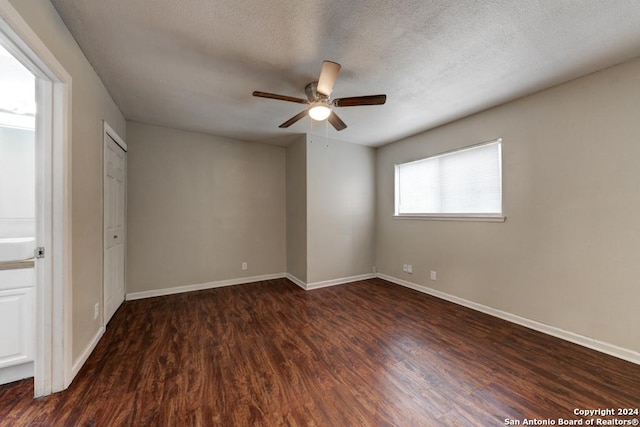 spare room with a textured ceiling, ceiling fan, and dark wood-type flooring