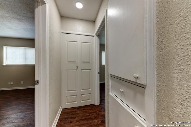 hall with a textured ceiling and dark hardwood / wood-style flooring