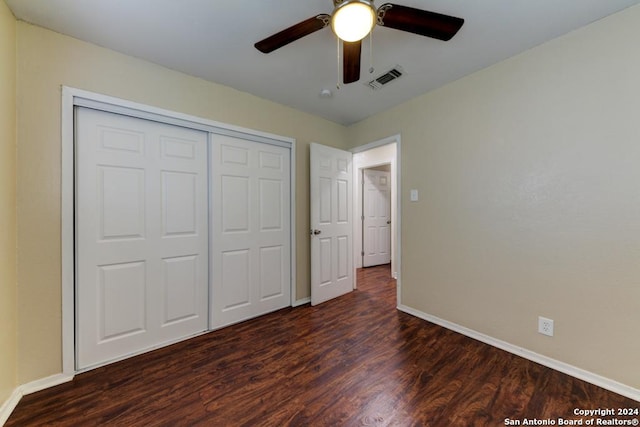 unfurnished bedroom with ceiling fan, a closet, and dark wood-type flooring