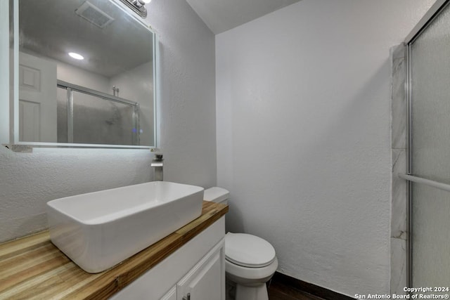 bathroom featuring wood-type flooring, vanity, a shower with shower door, and toilet