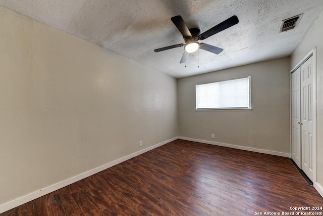 unfurnished bedroom with a textured ceiling, dark hardwood / wood-style floors, and ceiling fan