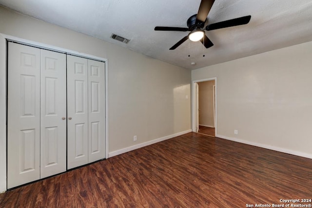 unfurnished bedroom with ceiling fan, dark hardwood / wood-style flooring, and a closet