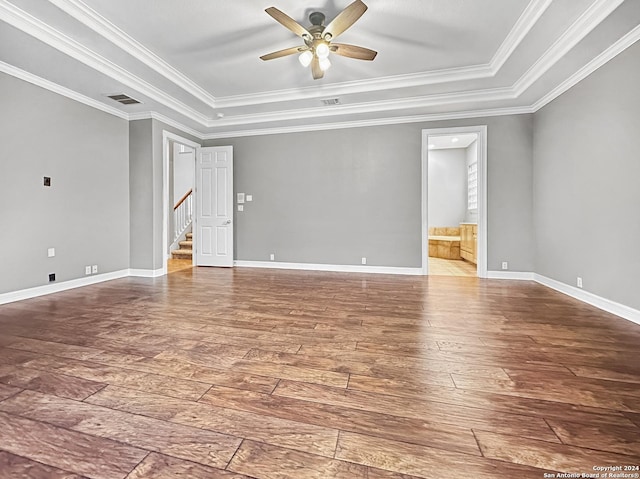 empty room with wood-type flooring, a tray ceiling, ceiling fan, and ornamental molding