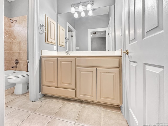 full bathroom with tile patterned flooring, vanity, tiled shower / bath combo, and toilet