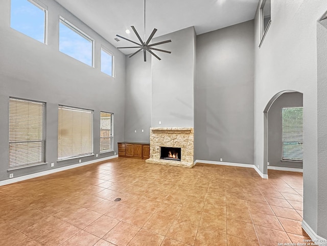 unfurnished living room with a fireplace, light tile patterned floors, and a high ceiling