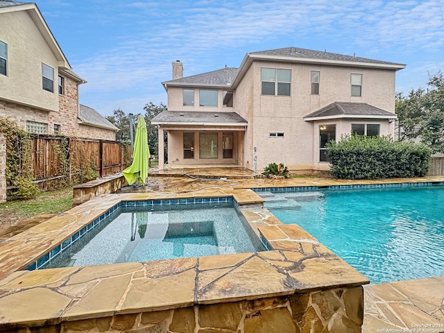 back of house featuring a swimming pool with hot tub