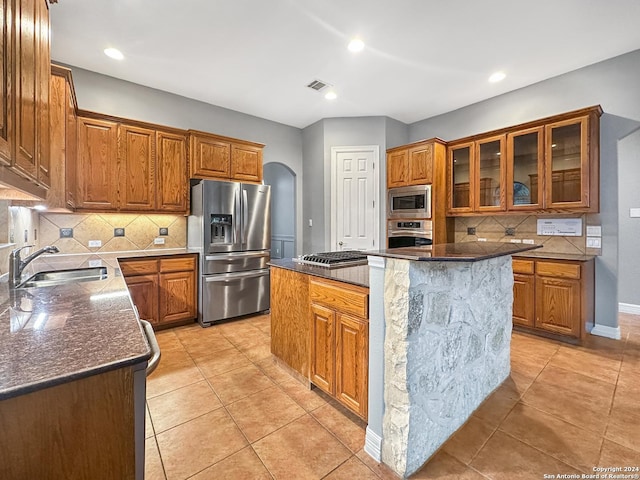 kitchen featuring a center island, backsplash, sink, dark stone countertops, and stainless steel appliances