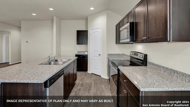 kitchen with dark brown cabinetry, sink, a center island with sink, appliances with stainless steel finishes, and light wood-type flooring