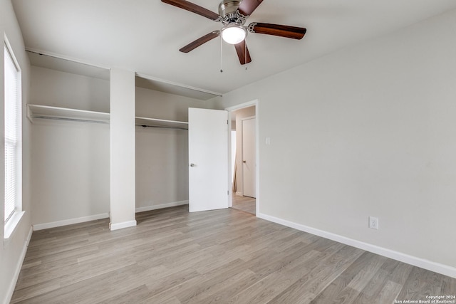 unfurnished bedroom featuring multiple windows, light hardwood / wood-style flooring, ceiling fan, and multiple closets