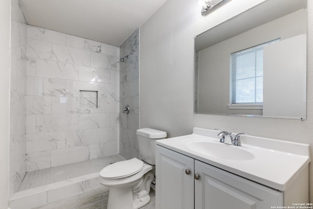 bathroom featuring tiled shower, vanity, and toilet