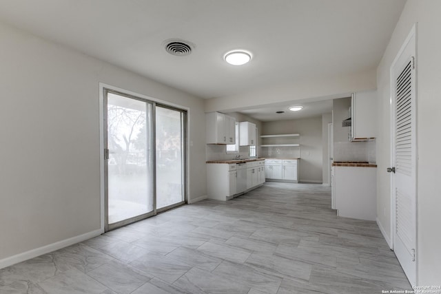 kitchen featuring white cabinets, decorative backsplash, and sink