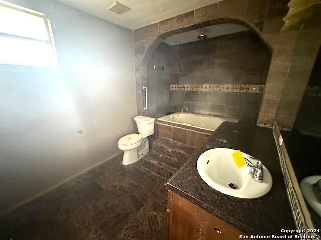 bathroom with vanity, toilet, and a tub